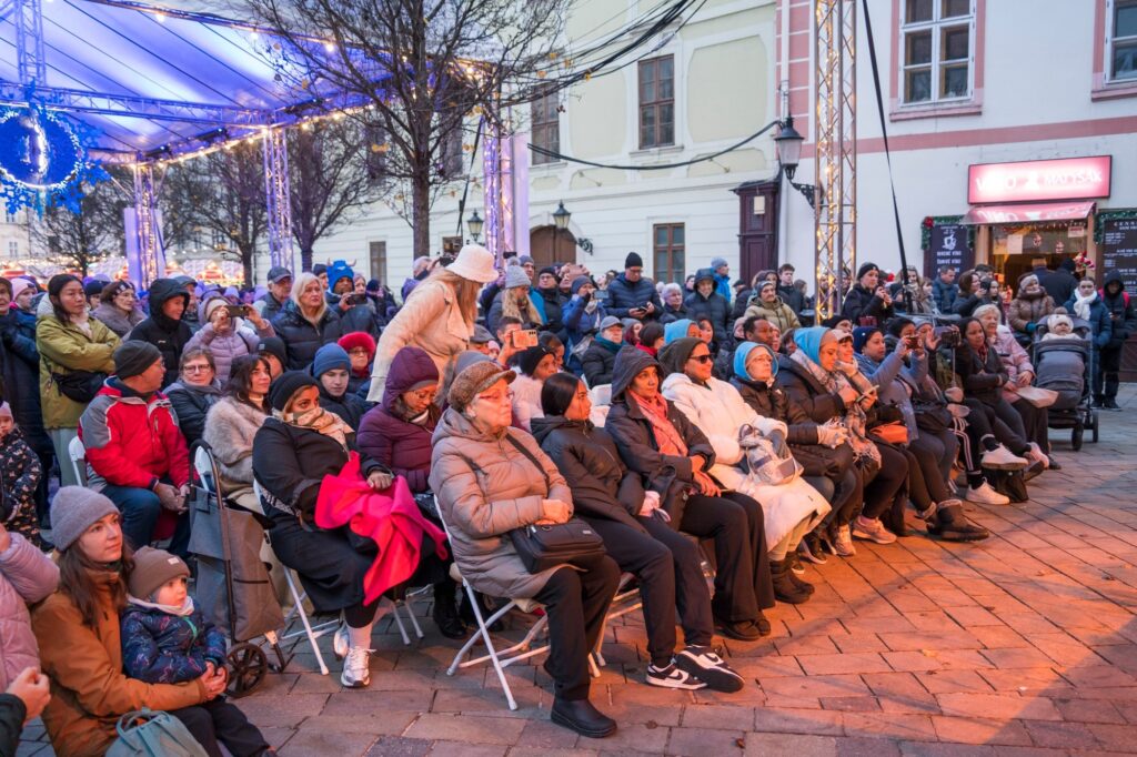Návštevníci a návštevníčky koncertu počas Bratislavských Vianoc sedia pred pódiom